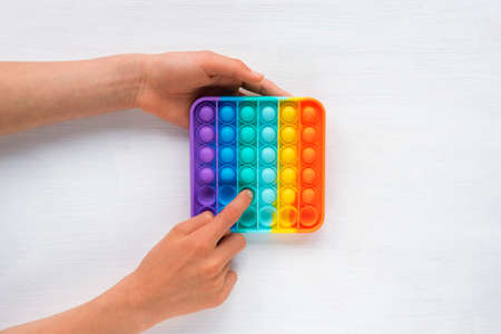 Childs hands playing with colorful poppit game. Pop it fidget toy. Top view, flat layの写真素材