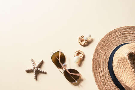 Flat lay with womens summer accessories on neutral background. Sunglasses, straw hat, earrings and starfish. Summer travel concept. Top view, copy spaceの写真素材