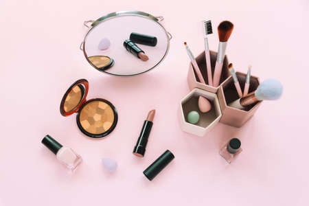 Blush, cosmetic brushes, lipstick, nail polishes and mirror on pink backgroung. Beauty, fashion concept. Top viewの写真素材