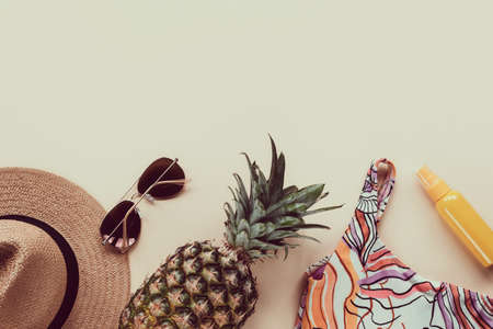 Flat lay with womans summer fashion traveler accessories top view background straw hat, sunglasses, pineapple, swimsuit and SPF cosmeticsの写真素材