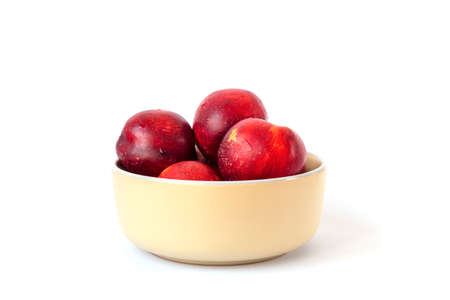 Ripe red peaches in a bowl isolated on white. Close up.の写真素材