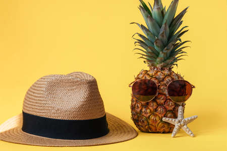 Straw hat, pinapple and starfish on yellow background. Summer vacation conceptの写真素材