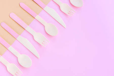 Disposable bamboo spoons, forks and knives on beige and pink background. Zero waste concept. Top view, copy space.の写真素材