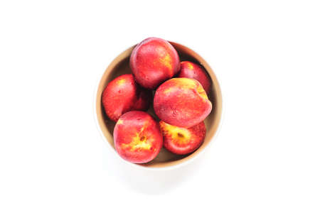 Ripe red peaches in a bowl isolated on white. Top view, flat lay.の写真素材