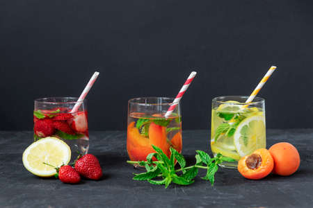 Three different summer healthy drinks, lemonade in glasses with straw on black background. Close up.の写真素材
