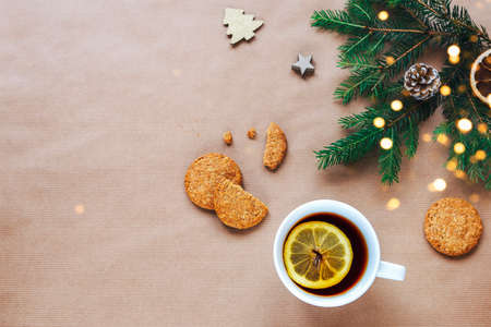 Christmas and New Year holiday background. Christmas tree branches, cup of tea and cookies on beige background. Top view, flat lay, copy space.の写真素材