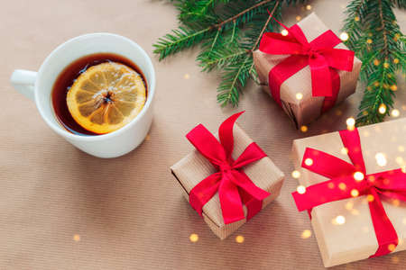 Christmas and New Year holiday background. Christmas tree branches, gift boxes, cup of tea and cookies on beige background. Top view, flat lay, copy space.の写真素材