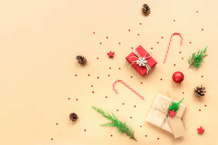 Christmas festive background. Gift boxes, candy canes, Christmas balls and confetti on beige...