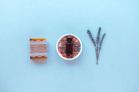 Lavender essential oil in brown glass bottle, Pink Himalayan salt, lavender blossom and soap bar on blue background. Skincare spa beauty bath cosmetic products for relaxation. Top view, flat lay.の写真素材