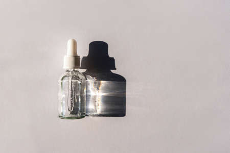 Bottle of natural skincare lotion on light grey background with harsh shadow. Trendy selfcare products. Top view, flat lay.の写真素材