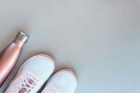 White sneakers and bottle with water on neutral gray background. Concept of healthy life, sport and training. Top view, flat lay, copy spaceの写真素材