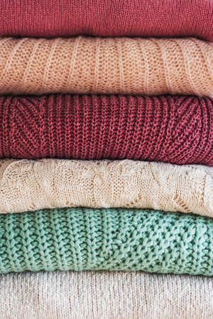 Stack of warm cozy knitted womens sweaters. Cozy autumn or winter clothes. Backgroundの写真素材