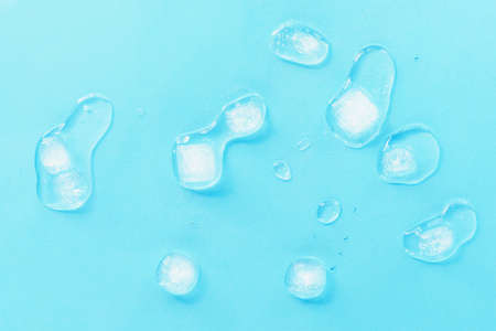 Melting ice cubes scattered on a blue background, top view. Texture.の写真素材