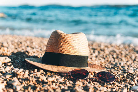 Sunglasses and straw hat on the beach. Summer vacation concept.