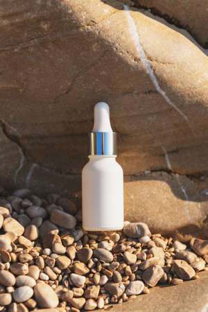 White bottle of cosmetic oil or serum on natural stone background. Natural cosmetics concept. Mock up.の写真素材