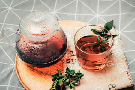 A mug of herbal tea and kettle on a wooden tray on the bed. Cozy autumn. Breakfast in bedroom. Top viewの写真素材