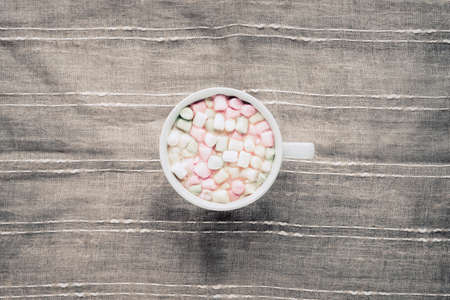 Cup of cocoa with marshmallows on a gray textile background. Top view, flat layの写真素材