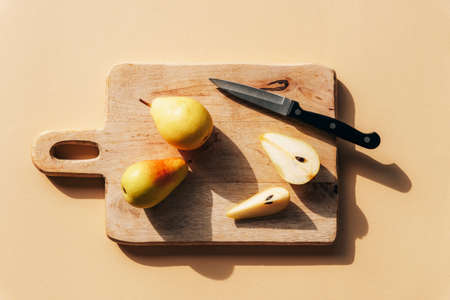 Fresh ripe pears and knife on wooden cutting board under hard sunlight. Top view, flat lay.の写真素材