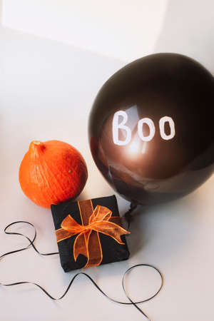 Gift in a box, orange hokkaido pumpkin, black balloon with word Boo on white background. Halloween concept.の写真素材