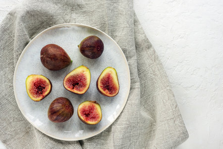 Fresh ripe figs on a plate on white table. Top view, flat lay.