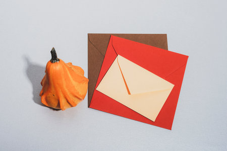 Colorful envelopes and pumpkin on a table. Autumn concept. Top view, mockup.の写真素材