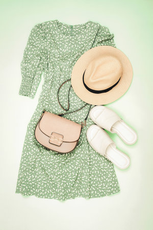 Summer casual style. Stylish woman outfit, dress, straw hat, sandals and handbag on light green background. Flat lay, top view.の写真素材