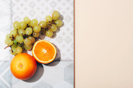 Oranges and grapes on vintage tile on beige background. Top view, flat lay, copy space.の写真素材