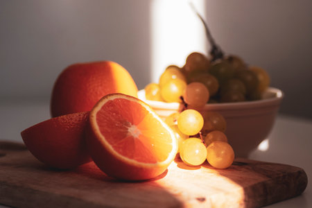 Oranges and grapes on cutting board in sunlight. Still life. Closeup.の写真素材