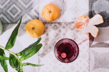 Glass with cold drink and mandarines on vintage tile background. Top view. Selective focus.の写真素材