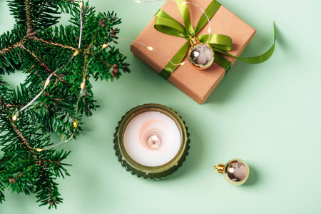 Christmas background with candle, gift box, fir branches and Christmas toys on green table. Top view, flat lay.の写真素材