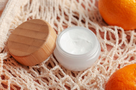 Bamboo cream jar on the background of cotton mesh bag and tangerines. Organic spa cosmetic beauty product. Zero waste conceptの写真素材