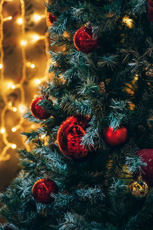 Amazing Christmas decorations on fir tree with red balls and Christmas lights, blurred background.