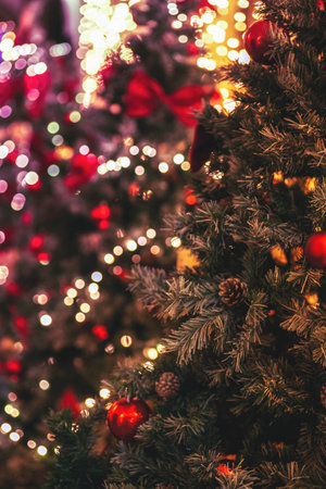 Christmas decorations on fir tree with golden and red balls and Christmas lights, closeup. Blurred bokeh backgroundの写真素材