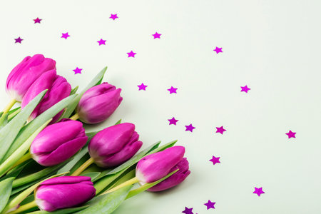 Bunch of purple tulips and star confetti background. Spring holidays concept. Top viewの写真素材