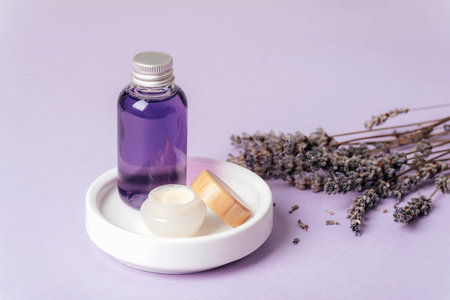 Lavender oil and cream on white dish and lavender flowers. Skin care, aromatherapy, selfcare concept. Closeup.の写真素材