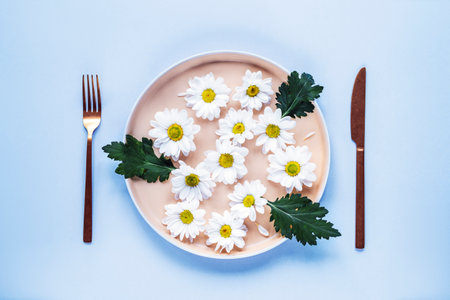 Plate with white flowers, fork and knife. Diet concept. Top view, flat lay.