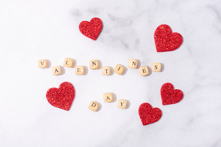 Wooden blocks with words Valentine's Day. Wooden letter blocks on marble background. Red hearts...