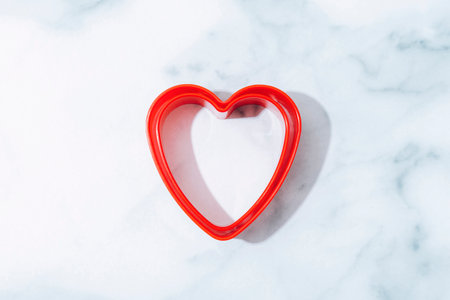 Creative holiday concept of love. Cookie cutter in a shape of heart on marble background....