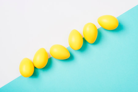 Yellow Easter eggs on white and blue background. Top view, flat lay, copy space.