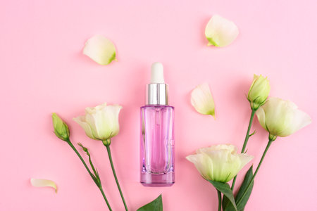 Purple cosmetic bottle and white eustoma flowers on pink background. Top view, flat lay.の写真素材