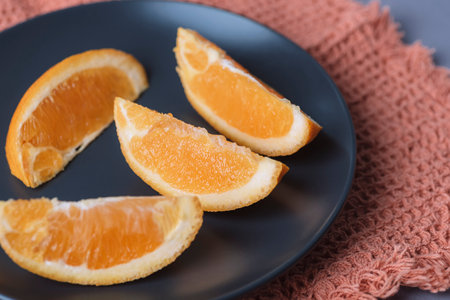 Orange slices on black plate, closeup. Selective focus