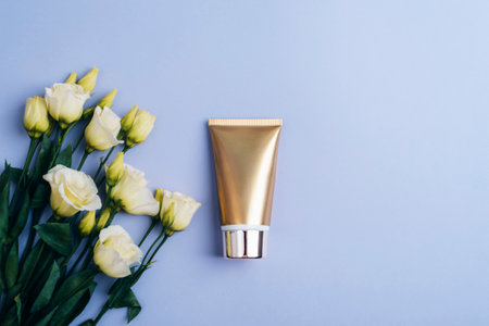 Golden cream tube and white eustoma flowers on purple background. Top view, flat lay.の写真素材