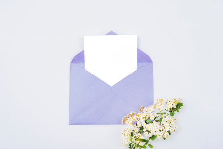 Envelope with blank card and white blossom on purple background. Birthday, Valentines day, Mothers day, Womens day concept. Top view, flat lay, mock up.の写真素材