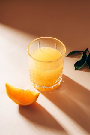 Orange juice on beige table with long shadows. Healthy drink. Closeupの写真素材