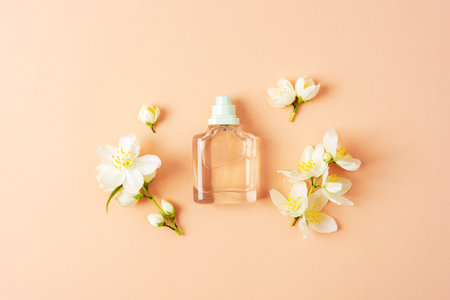 Perfume glass bottle and white jasmine flowers on peachy background. Top view, flat lay.の写真素材