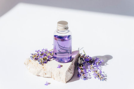 Lavender oil in transparent bottle on stone podium in sunlight. Natural cosmetics, aromatherapy concept. Closeup.の写真素材