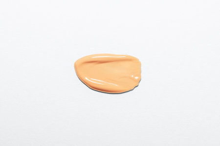 Cosmetic foundation swatch on white background. Texture of smeared beige foundation. Skincare cosmetic product nude sample. Concealer for perfect skin tone.の写真素材