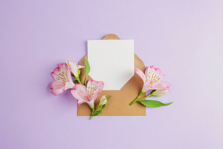 Envelope with blank card and pink alstroemeria flowers on lilac background. Birthday, Valentines day, Mothers day, Womens day concept. Top view, flat lay, mock up.の写真素材