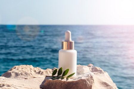 Cosmetic serum bottle on stone on the background blue sea in sunlight, closeup.の写真素材