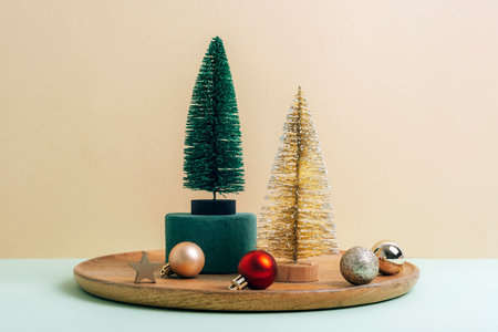 Christmas decorations, fir trees and balls on a wooden tray on beige background. Winter holidays concept.の写真素材
